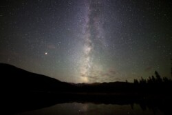 The Milky Way faintly reflects off the still surface of Echo Lake near Mt. Evans, Colorado.