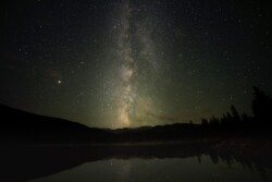 The Milky Way faintly reflects off the still surface of Echo Lake near Mt. Evans, Colorado.