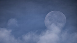 A gibbous Moon, just a few days past full, is obscured slightly by clouds on an otherwise clear morning. A gibbous Moon, just a few days past full, is obscured slightly by clouds on an otherwise clear morning.